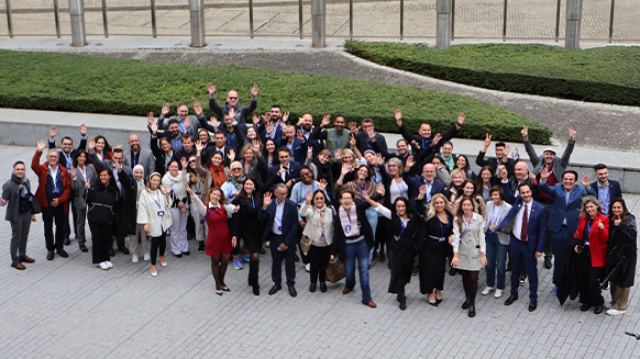 Gruppenfoto mit Teilnehmenden des EU-Policy-Camps 2024. Die Personen stehen in einer Gruppe zusammen, im Hintergrund ist ein Rasen und ein Gebäude zu sehen.